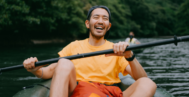 Young man of east asian descent smiling whilst in a canoe on the water Young man of east asian descent smiling whilst in a canoe on the water